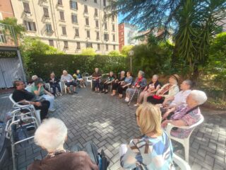 Ospiti di Casa Serena svolgono esercizi di ginnastica dolce nel giardino, guidati dalla fisioterapista