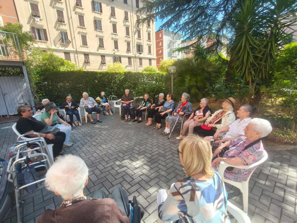 Ospiti di Casa Serena svolgono esercizi di ginnastica dolce nel giardino, guidati dalla fisioterapista